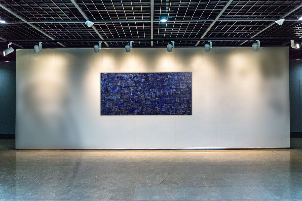 Denim original abstract painting by Alli Cullimore displayed in a gallery under spotlights — 152.5×76cm large-scale acrylic on canvas in deep indigo and blue with white highlights