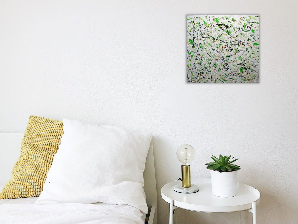 Green Pastures original abstract painting by Alli Cullimore displayed in a bright minimal bedroom — 41×41cm acrylic on canvas with splattered dark and light greens on a white textured base